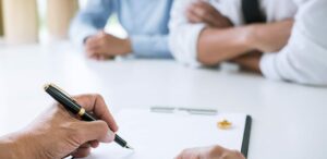 Lawyer signing divorce documents with couple discussing terms of an uncontested divorce.